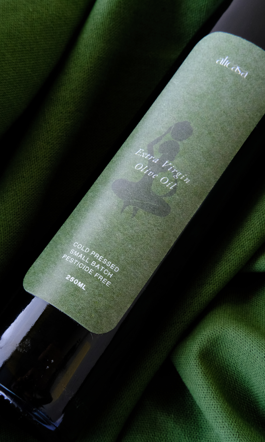cold-pressed olive oil bottle on green linen cloth cape town
